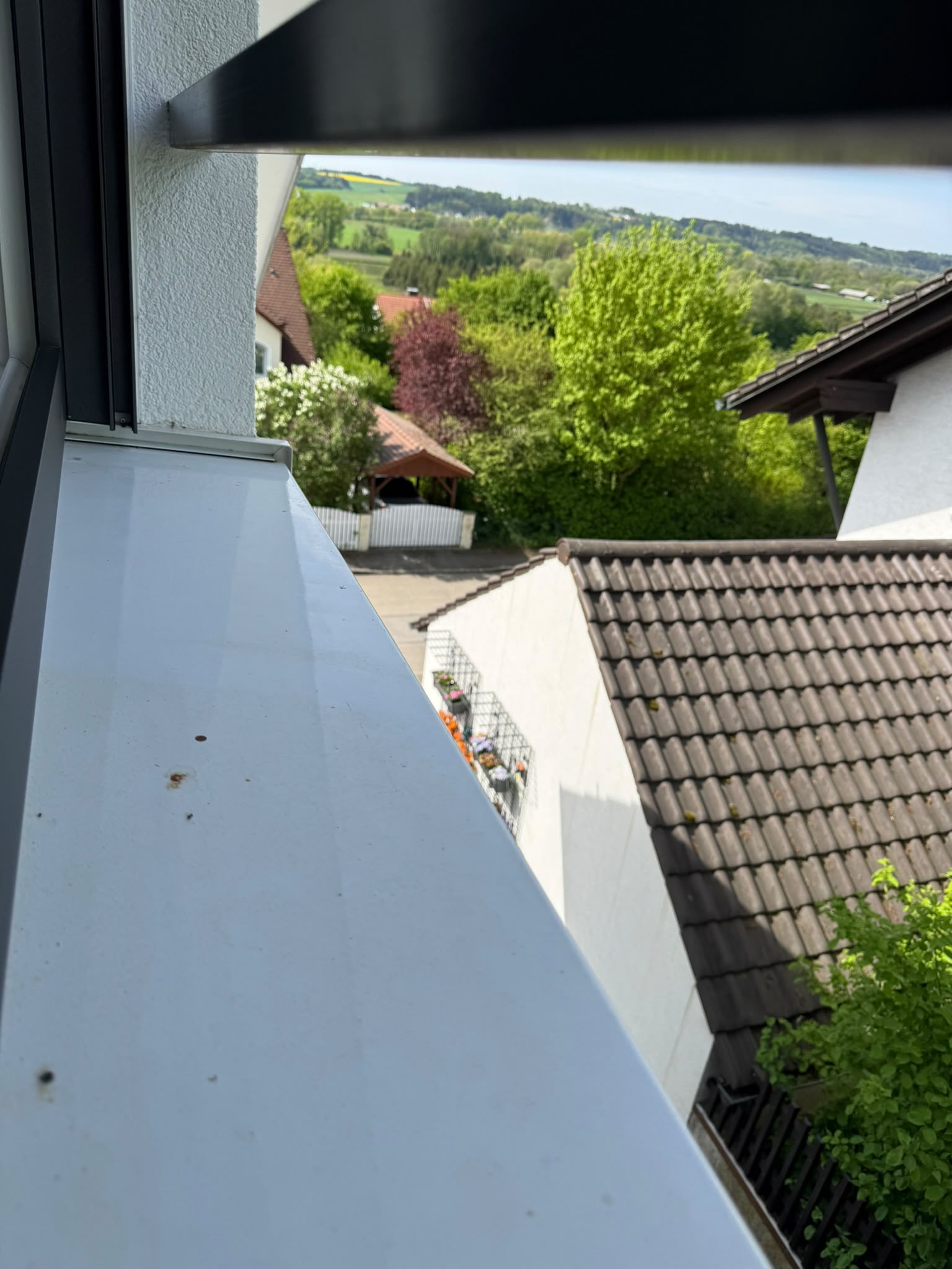 Saubere aeussere Fensterbank mit Blick ueber Daecher und Huegel