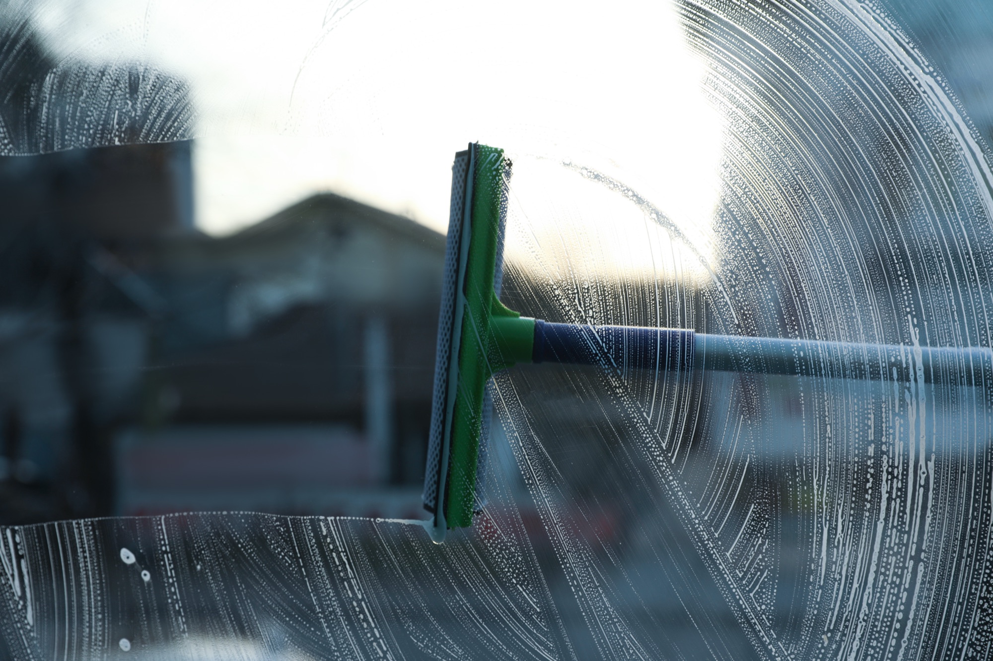 Fensterreinigung mit dem Abzieher auf einer eingeseiften Scheibe