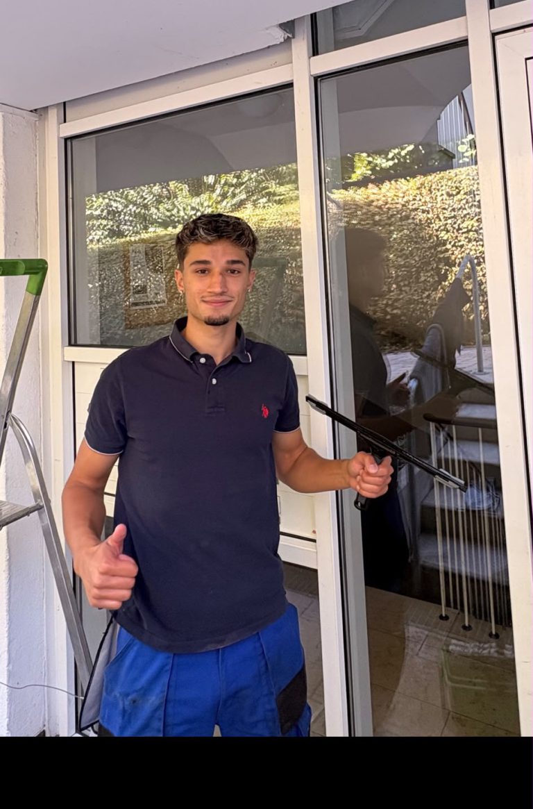 Mitarbeiter von Clean View mit Fensterabzieher vor einer Glasfassade